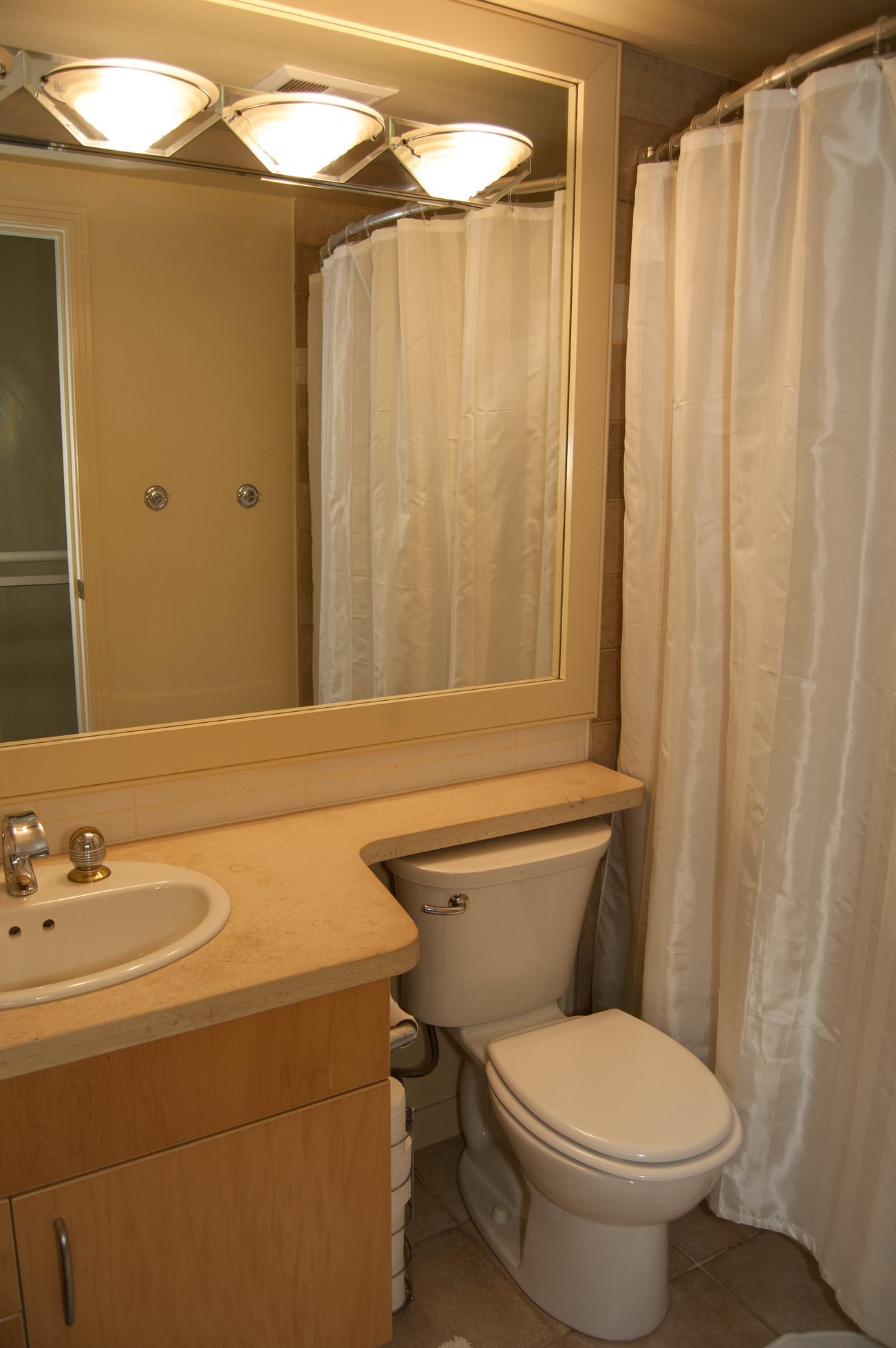 Bright bathroom with beige countertop and white toilet, reflected in mirror. - TH A- 1199 Marinaside Cres, Vancouver Downtown