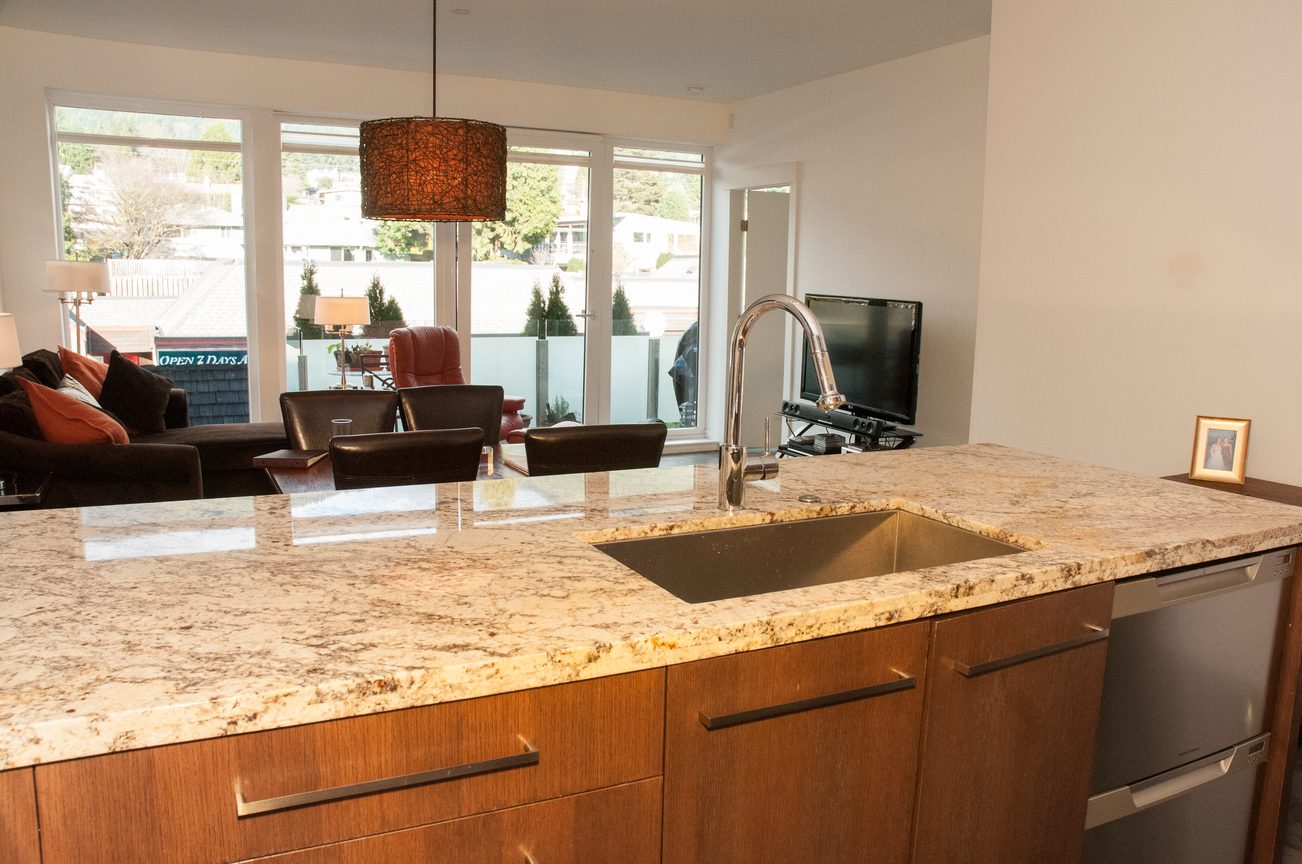 Bright kitchen with granite countertops and a view of the living area. - 306-650 Evergreen Place, North Vancouver