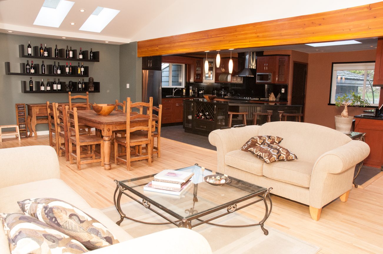 Open-concept living and dining area with hardwood floors, modern kitchen, and wine storage. - 5646 Westport Rd, West Vancouver