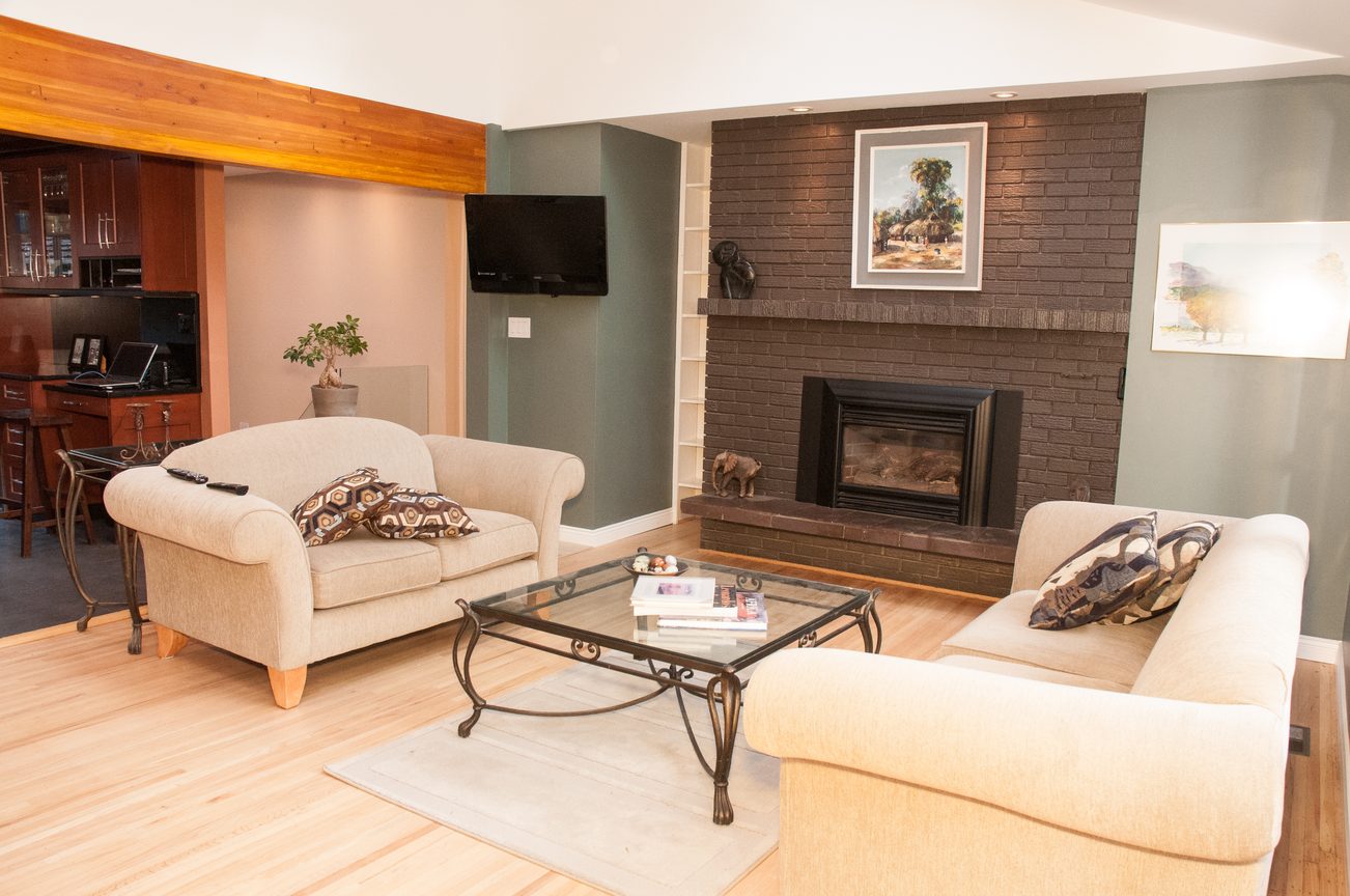 Furnished living room with hardwood floors, brick fireplace, and modern decor. - 5646 Westport Rd, West Vancouver