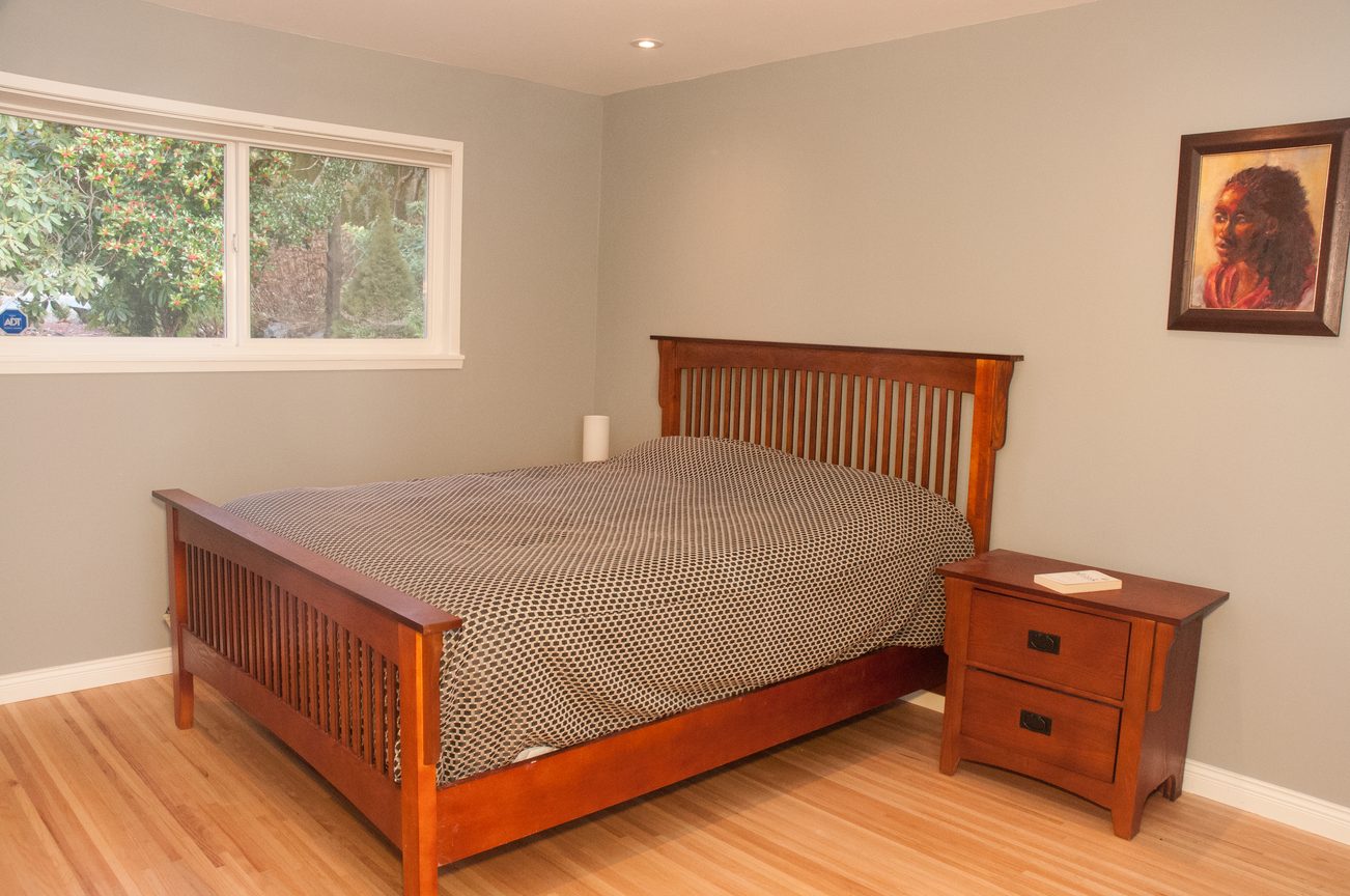Spacious bedroom with wooden bed frame and hardwood floors. - 5646 Westport Rd, West Vancouver