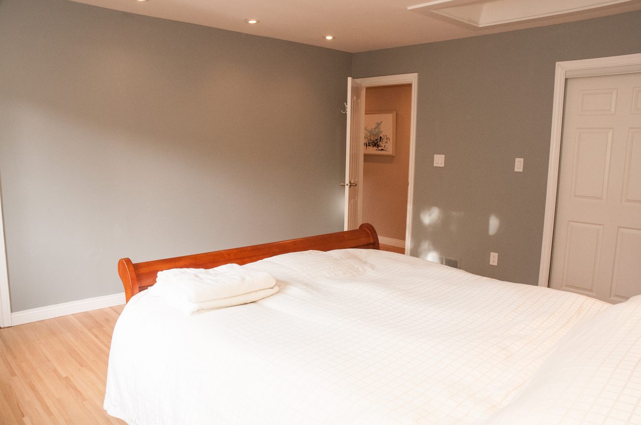 Spacious bedroom with hardwood floors and a neatly made bed. - 5646 Westport Rd, West Vancouver