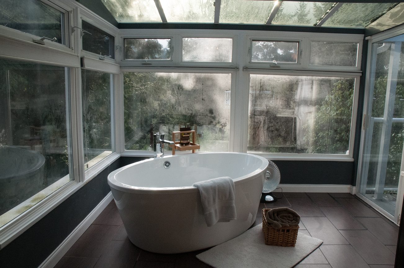 Bright bathroom with large soaking tub and expansive glass windows. - 5646 Westport Rd, West Vancouver