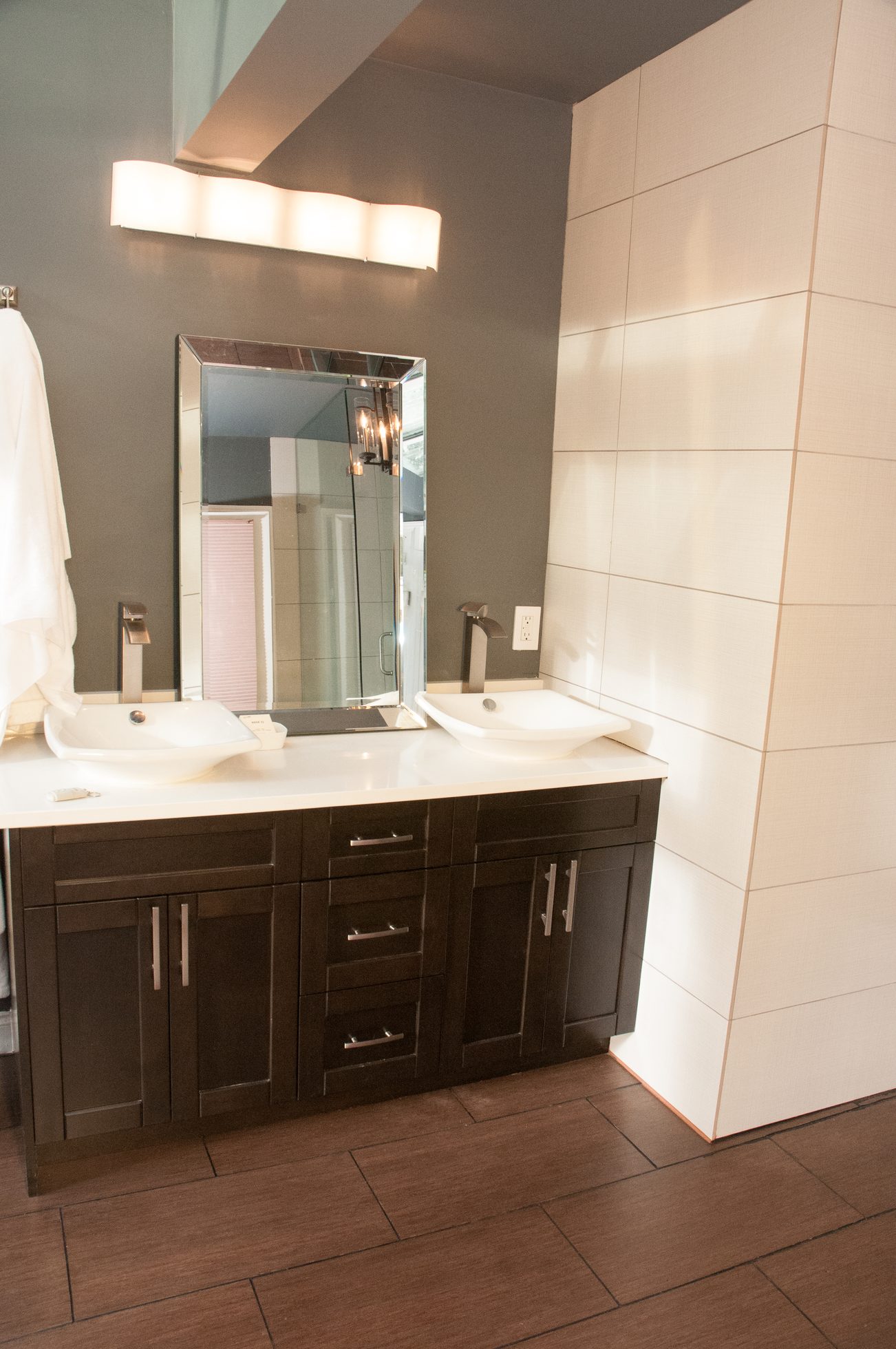 Modern bathroom with dual sinks, dark cabinets, and white countertops. - 5646 Westport Rd, West Vancouver