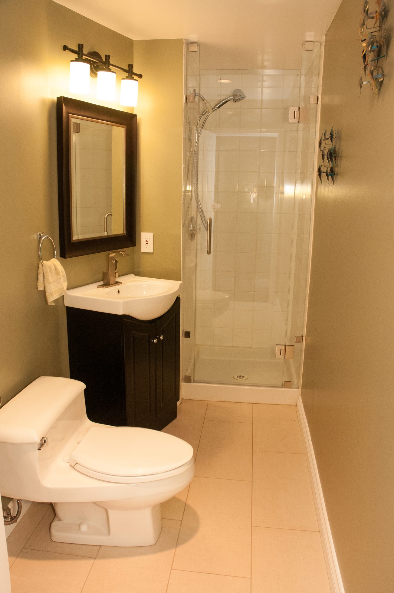 Small bathroom with black vanity, glass shower, and beige walls. - 5646 Westport Rd, West Vancouver