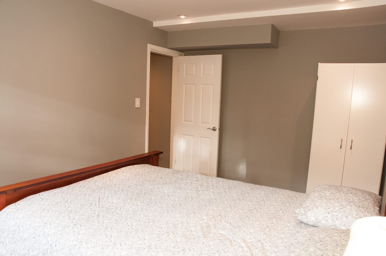 Furnished bedroom with white closet and wooden bed frame. - 5646 Westport Rd, West Vancouver