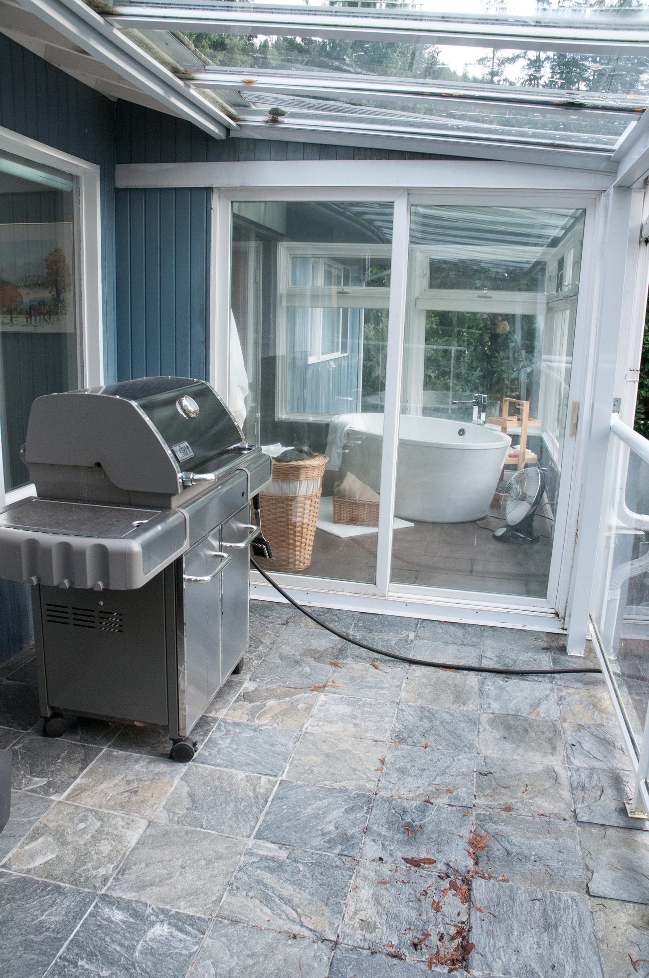 Bright sunroom with stone flooring, outdoor grill, and view of trees. - 5646 Westport Rd, West Vancouver