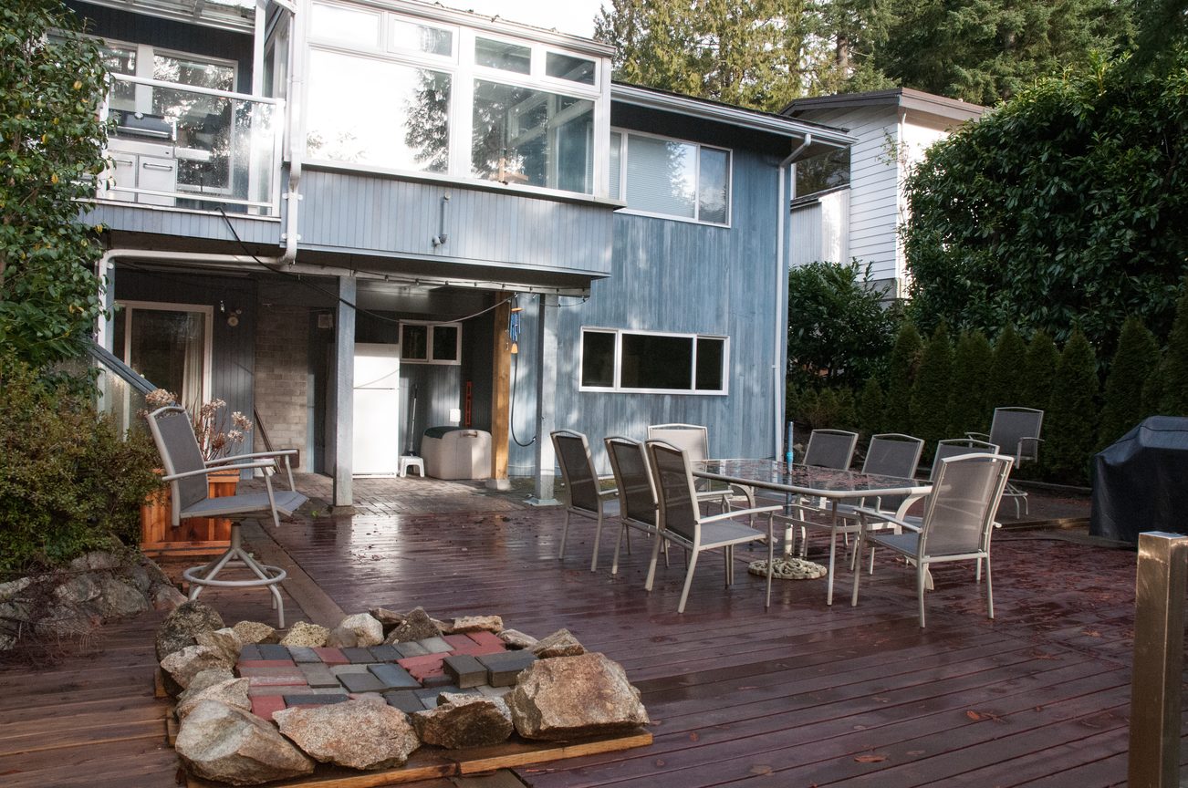 Furnished patio with a fire pit and outdoor dining set, surrounded by greenery. - 5646 Westport Rd, West Vancouver