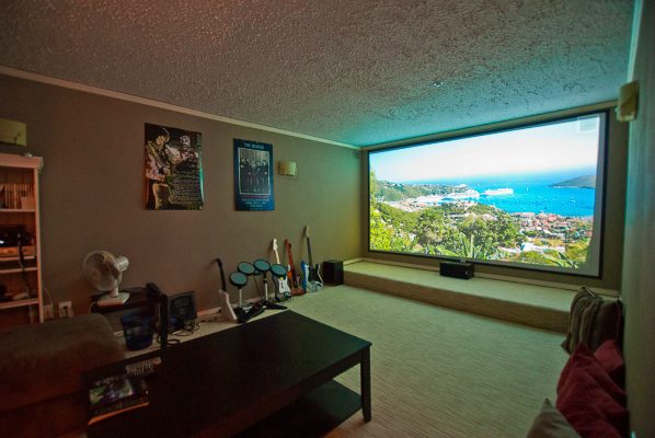 Living room with a large window showing a scenic view, a coffee table, and guitar wall decor. - 8571 Seascape Lane, West Vancouver
