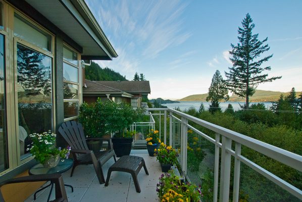 Furnished balcony with a view of the lake and mountains, adorned with potted flowers and outdoor furniture. - 8571 Seascape Lane, West Vancouver