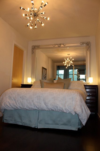 Furnished bedroom with elegant mirror, chandelier, and cozy bedding. - 702- 546 Beatty Street, Vancouver Downtown