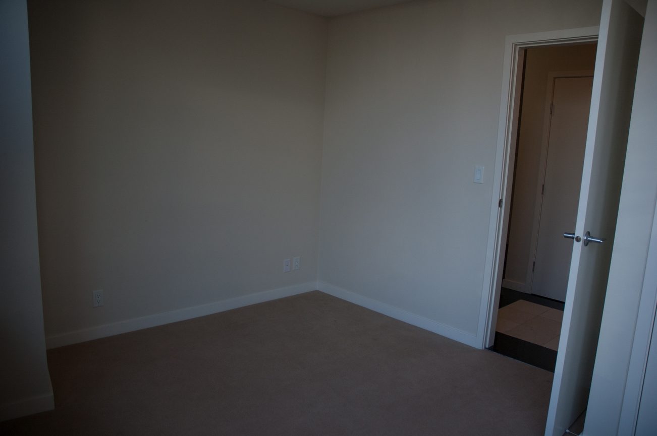 Empty living room with beige walls and carpeted floor. - 100-9 Smithe Mews, Vancouver Downtown