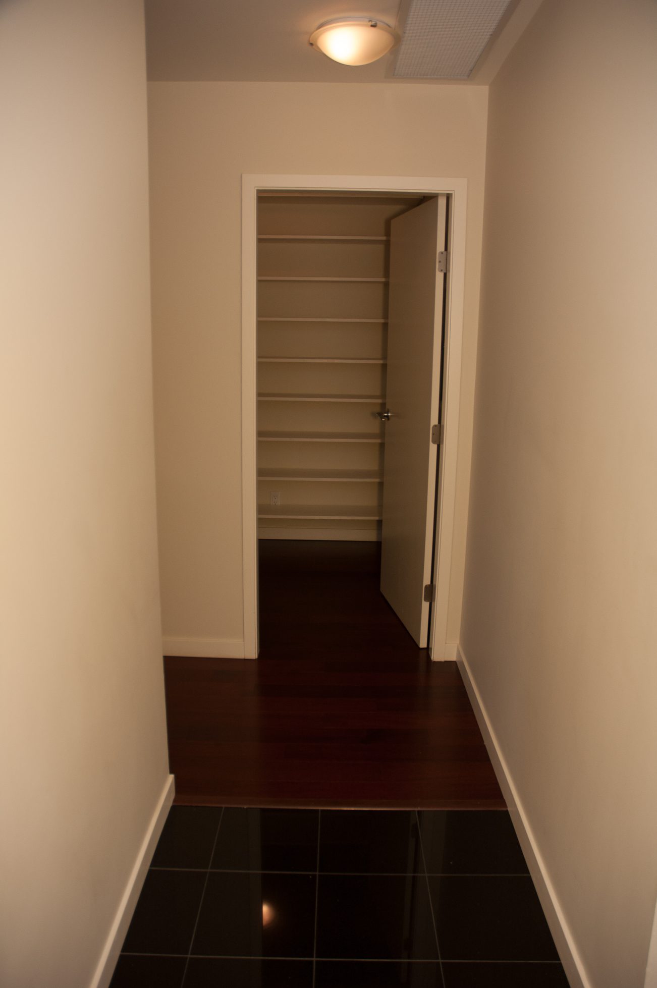 Framed closet with built-in shelves and dark hardwood floors. - 100-9 Smithe Mews, Vancouver Downtown