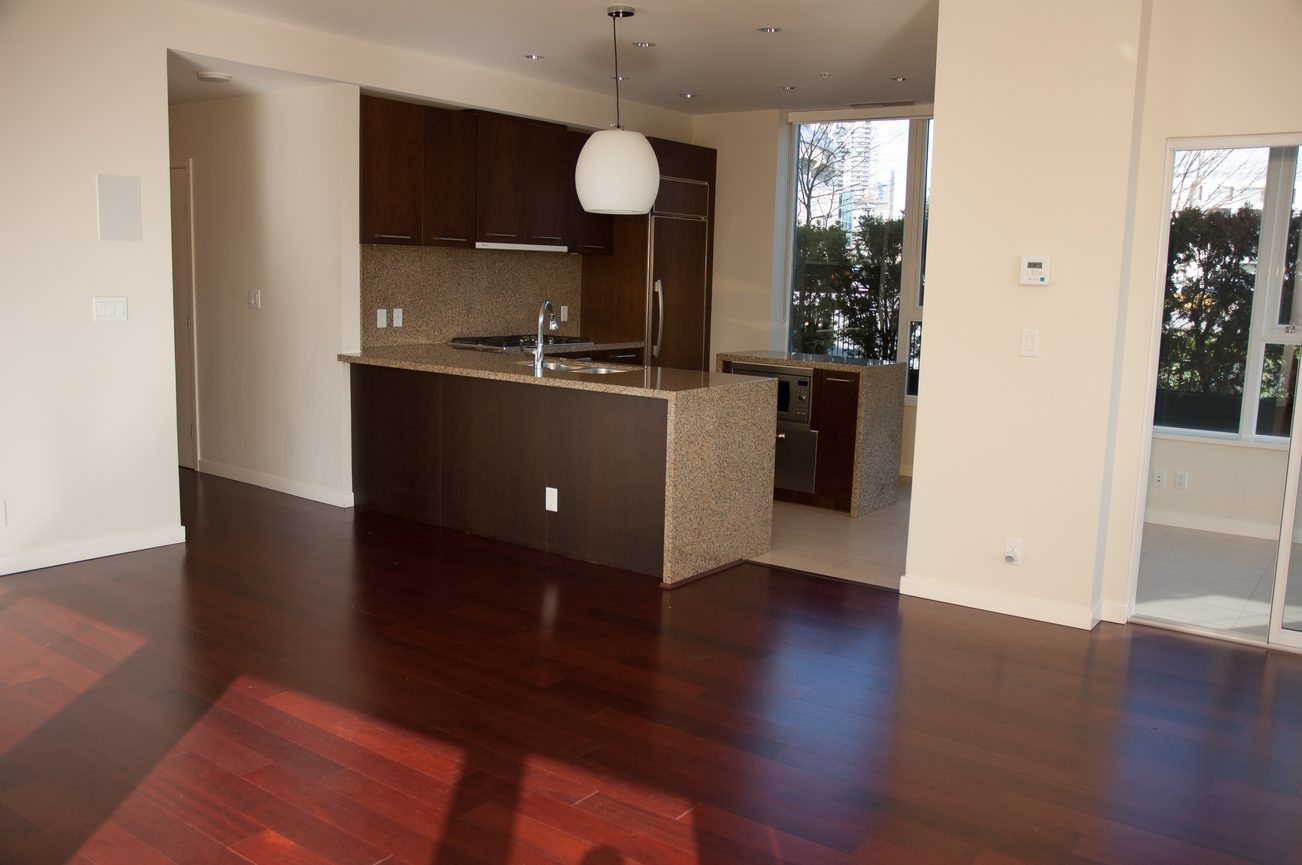 Bright kitchen with dark wood cabinets, granite countertops, and hardwood floors, featuring a city view through large...