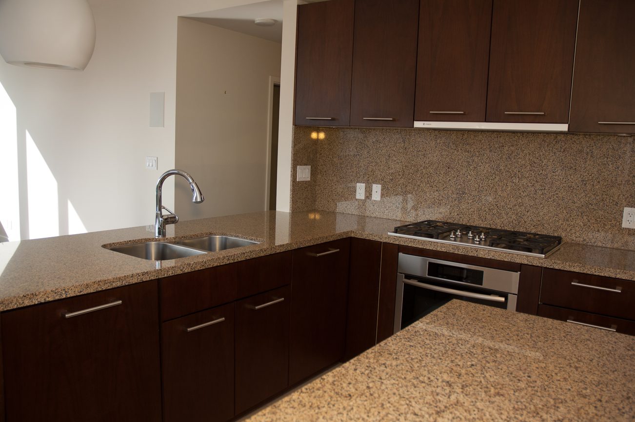 Bright kitchen with granite countertops and dark wood cabinets, modern design. - 100-9 Smithe Mews, Vancouver Downtown
