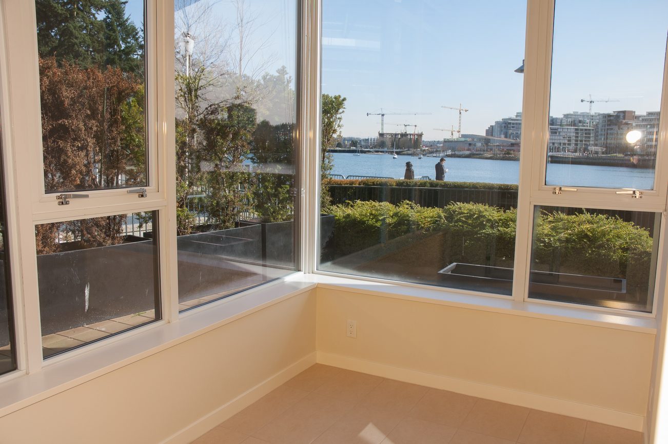 Bright living room with large windows offering a stunning city view and waterfront access. - 100-9 Smithe Mews, Vancouver Downtown