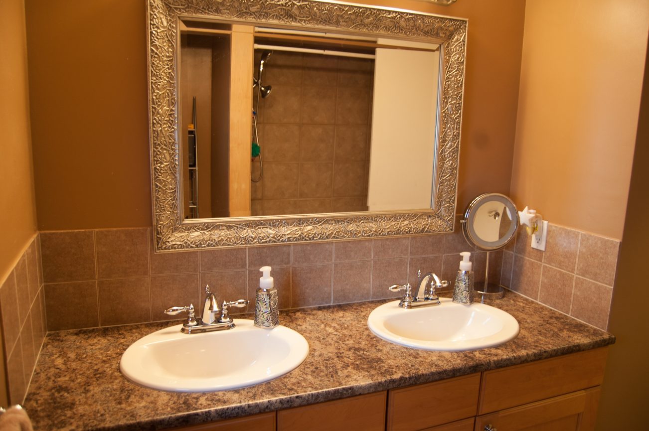Bathroom with double sinks, granite countertops, and ornate mirror. - MAIN - 451 East Keith Road, North Vancouver