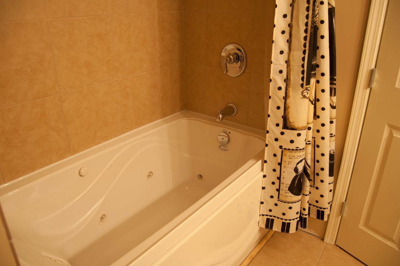 Bathroom with corner tub, polka-dot shower curtain, beige tiles. - MAIN - 451 East Keith Road, North Vancouver
