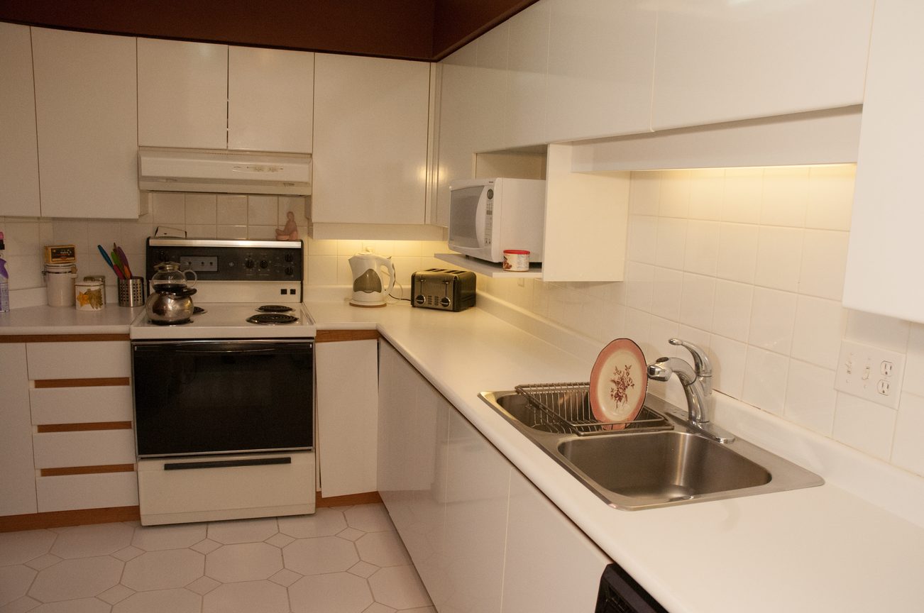 Bright kitchen with white countertops, hexagonal tile floor, and a small dishwasher. - 204 -106 West Kings Road, North Vancouver