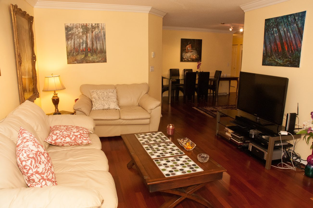 Living room with hardwood floors, cozy furniture, and a large flat-screen TV. - 204 -106 West Kings Road, North Vancouver