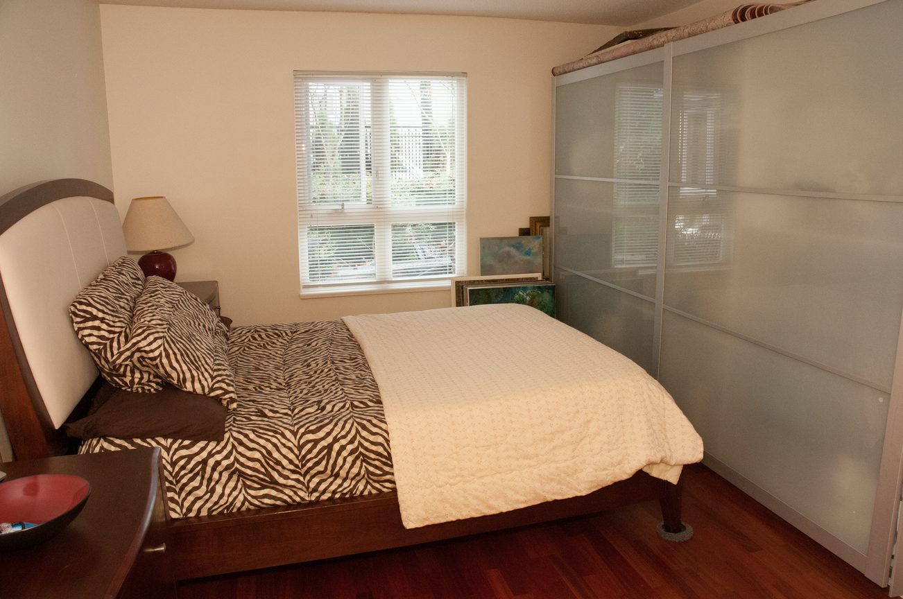 Bright bedroom with zebra print bedding and sliding glass closet doors. - 204 -106 West Kings Road, North Vancouver