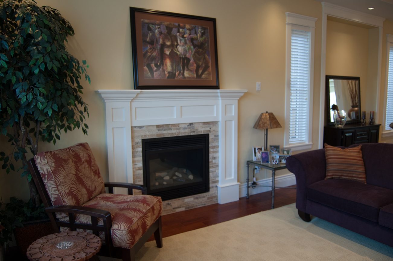 Furnished living room with a fireplace, hardwood floors, and a cozy armchair. - 186 West 23rd Ave, Vancouver West Side