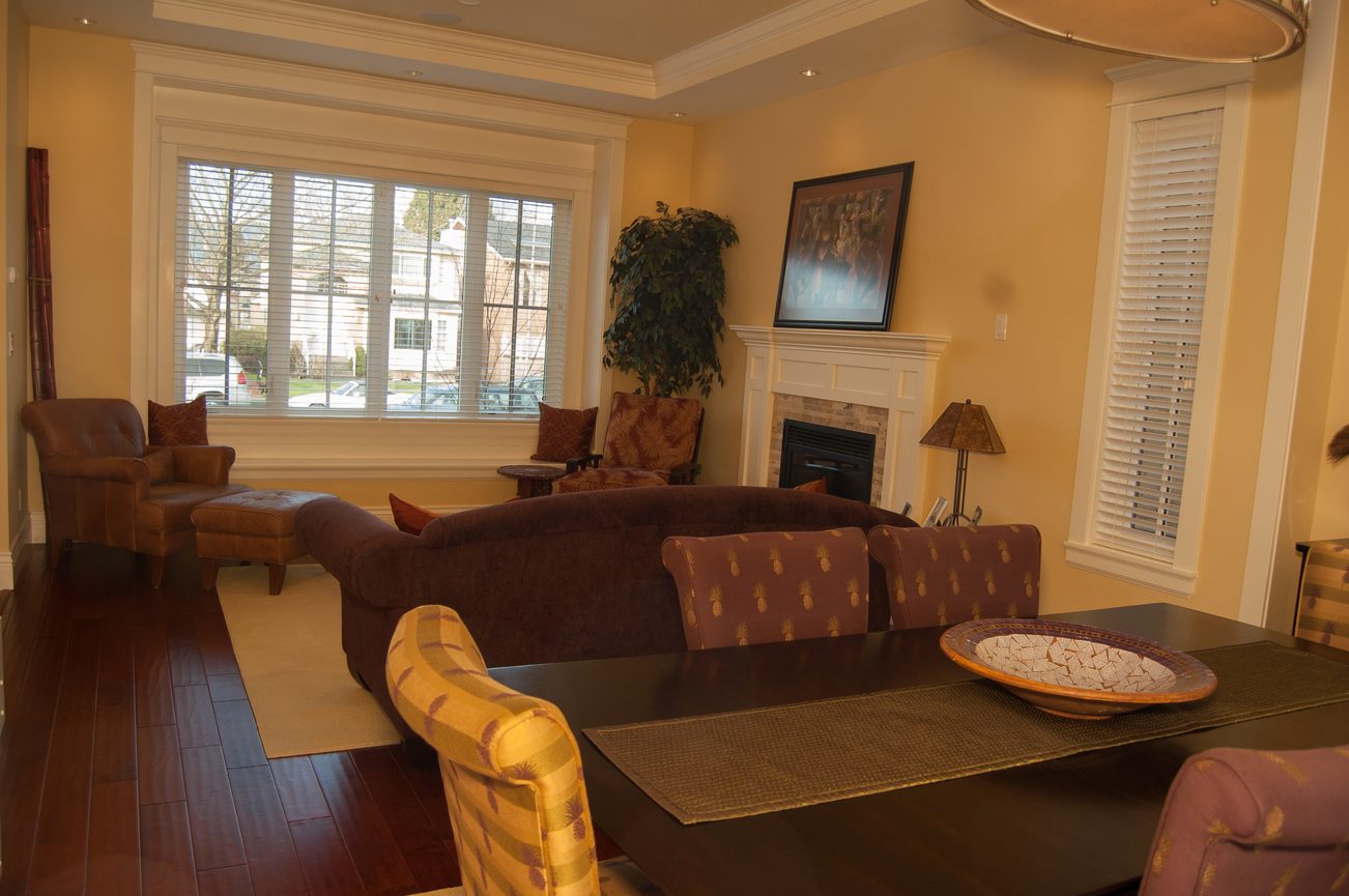 Furnished living room with hardwood floors, large windows, and a cozy fireplace. - 186 West 23rd Ave, Vancouver West Side