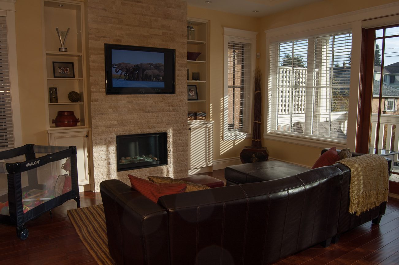 Bright living room with a fireplace, large windows, and a flat-screen TV above it. - 186 West 23rd Ave, Vancouver West Side