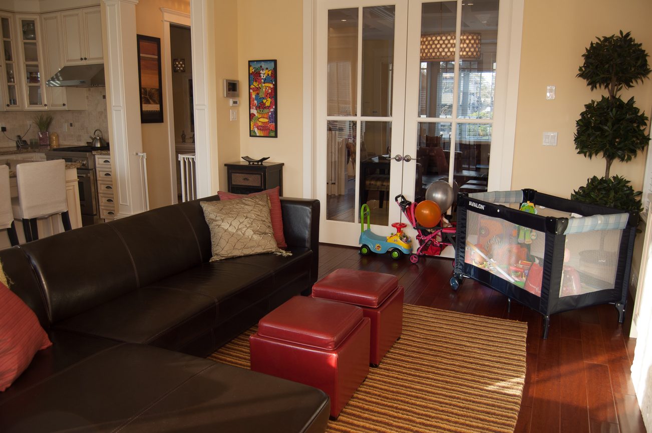 Living room with hardwood floors, leather couch, and baby playpen. - 186 West 23rd Ave, Vancouver West Side