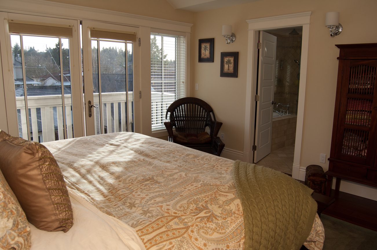 Spacious bedroom with large windows, city view, and a cozy reading chair. - 186 West 23rd Ave, Vancouver West Side
