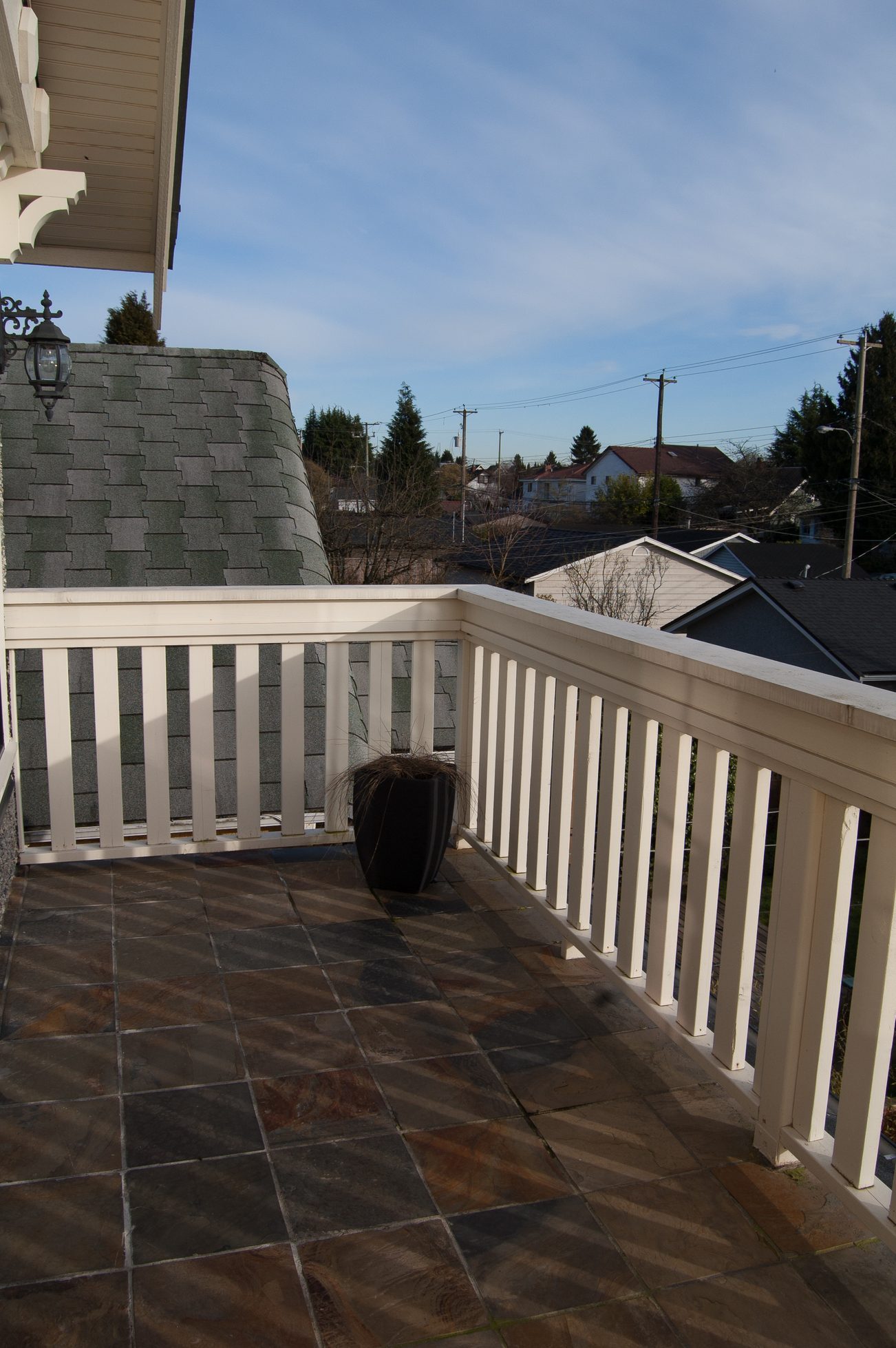 Balcony with stone flooring and white railing, overlooking neighborhood rooftops. - 186 West 23rd Ave, Vancouver West Side