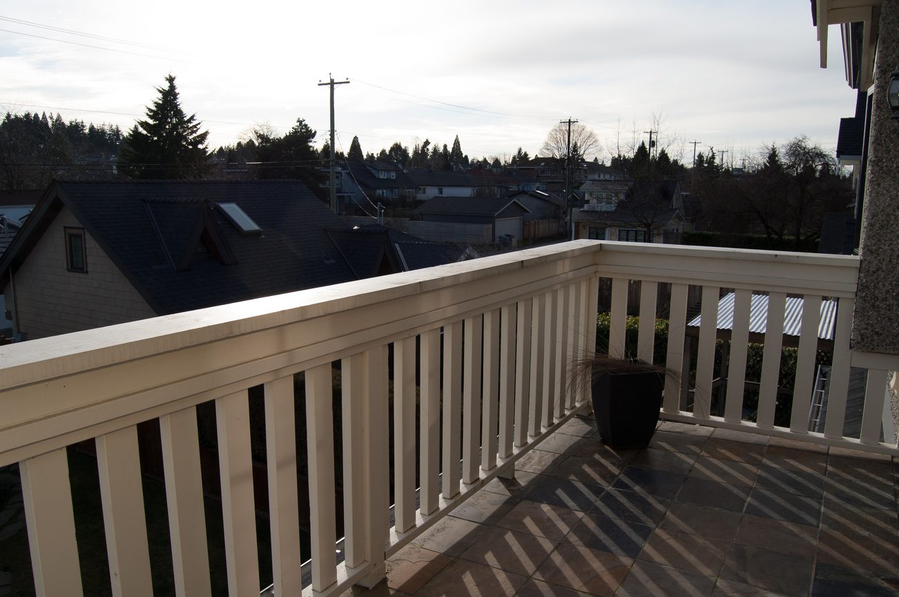 Balcony with white railings, city view, and stone flooring. - 186 West 23rd Ave, Vancouver West Side