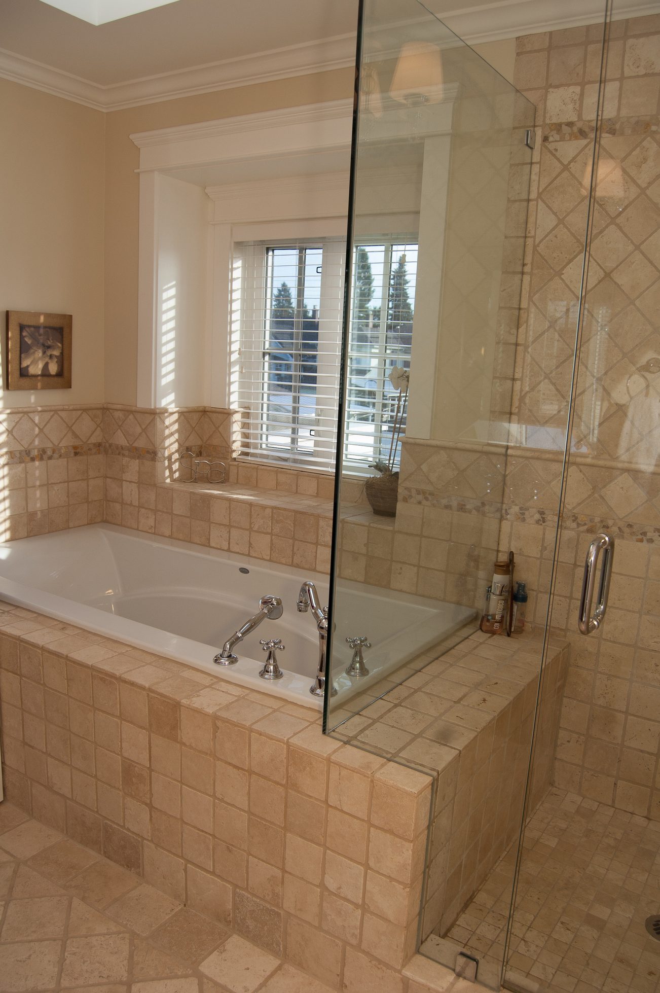 Spacious bathroom with a large soaking tub and glass shower, featuring beige tiles and a window with blinds. - 186 West 23rd Ave, Vancouver West Side