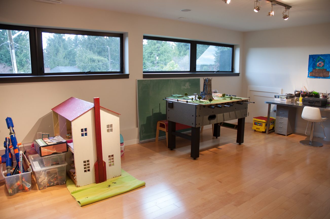 Bright playroom with hardwood floors, a foosball table, and a dollhouse, perfect for kids. - 3925 Viewridge Place, West Vancouver