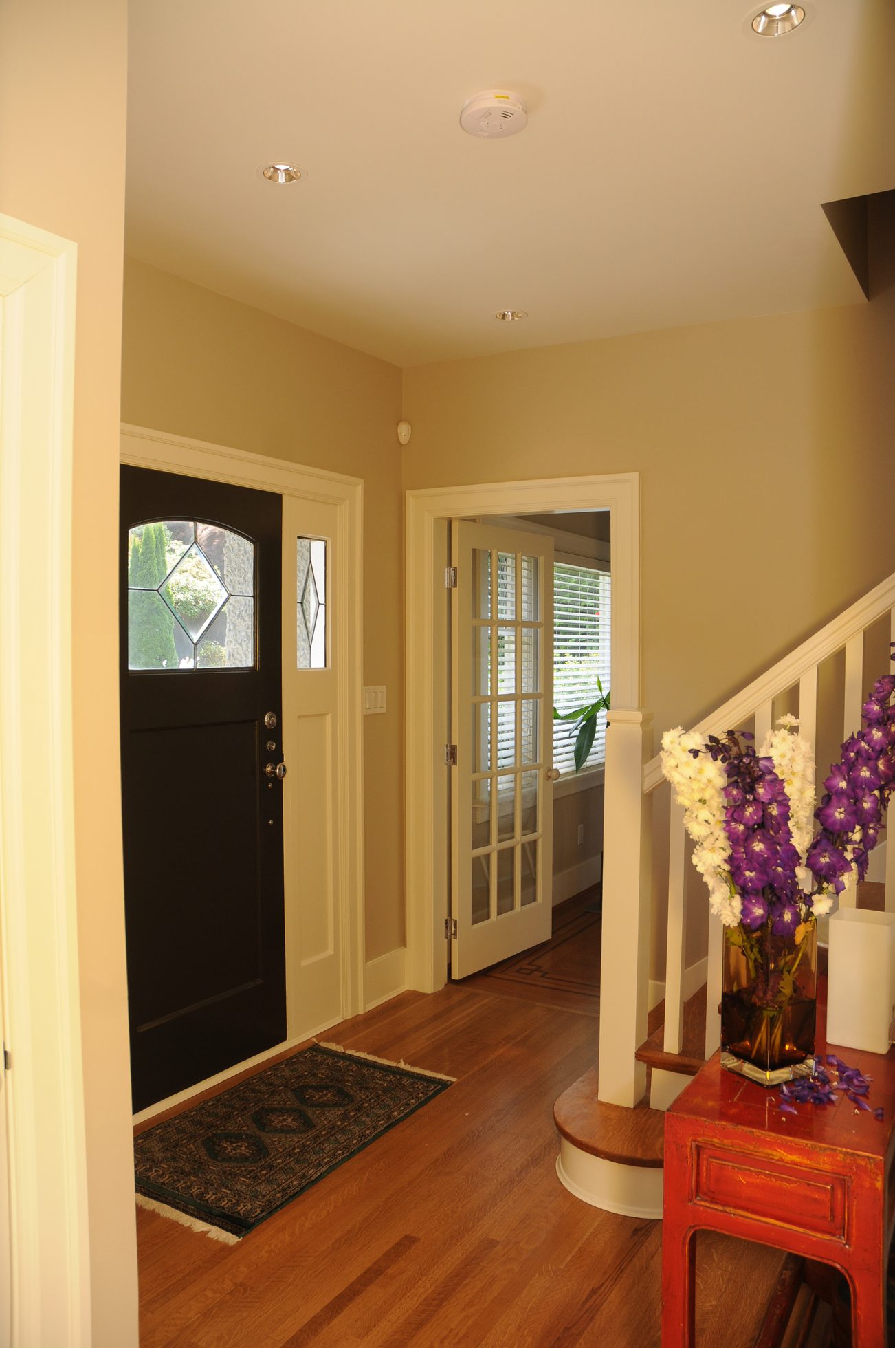 Foyer with hardwood floors, a black door, and a red console table with flowers. - 2037 Quilchena Crescent, Vancouver West Side