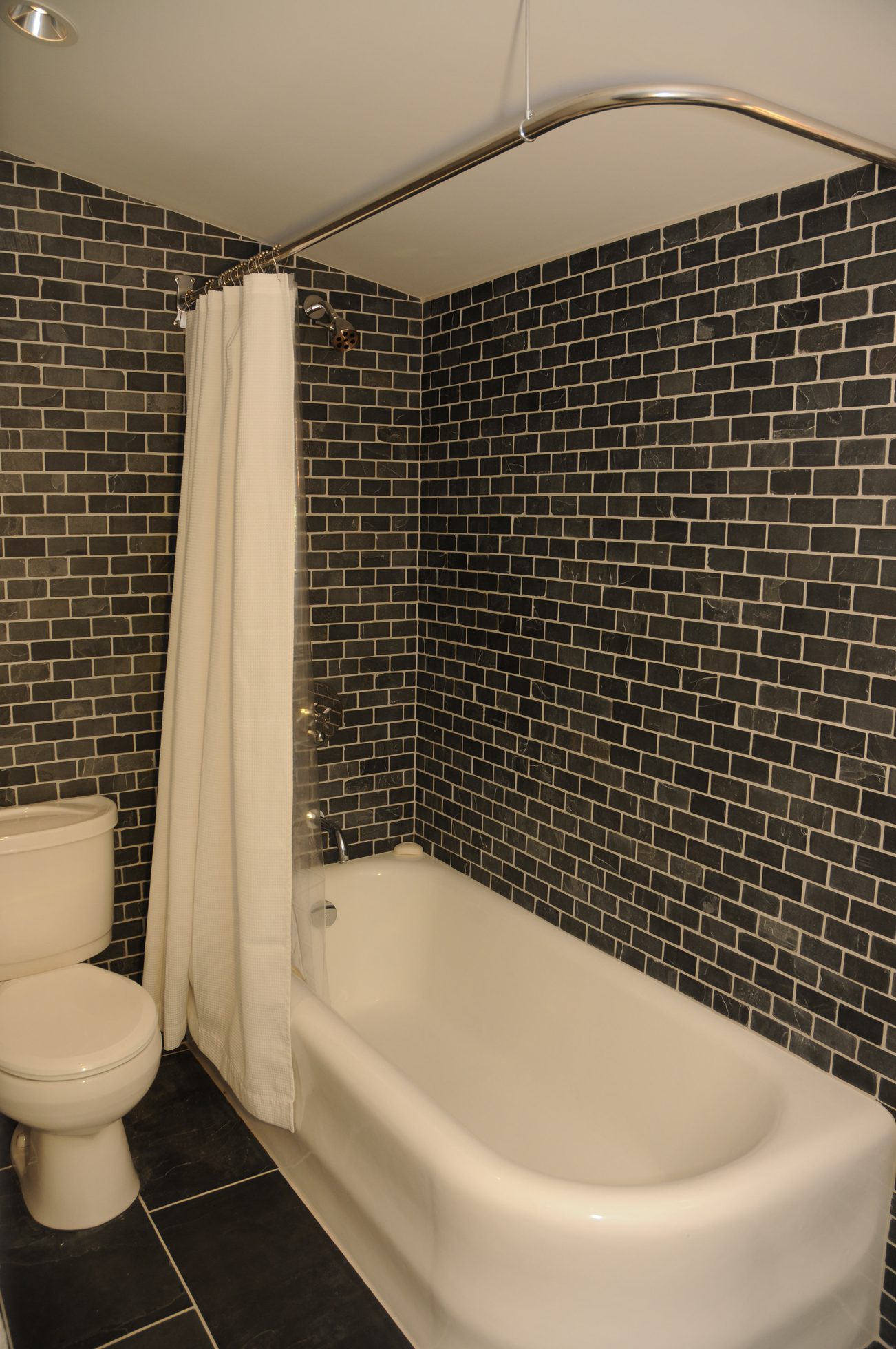 Furnished bathroom with black brick tile walls and a white bathtub. - 2037 Quilchena Crescent, Vancouver West Side