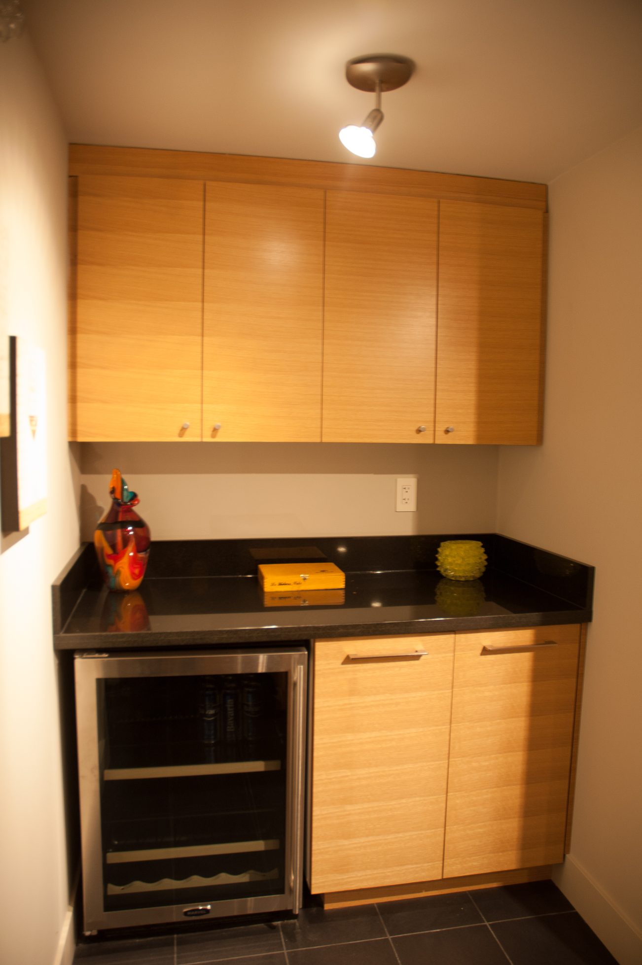 Bright kitchen with sleek black countertops, wooden cabinets, and a wine fridge. - 621 Kenwood Road, West Vancouver