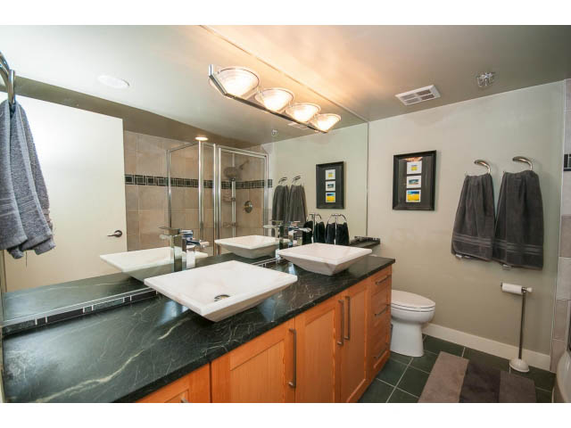 Furnished bathroom with black marble countertops and wooden cabinets. - 2901 - 1199 Marinaside, Vancouver Downtown