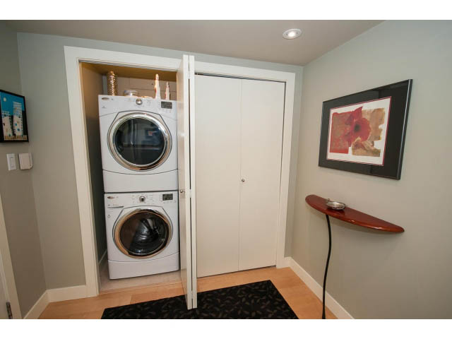 Bright laundry room with white appliances and sliding doors, hardwood floors, and a red poppy artwork on the wall.