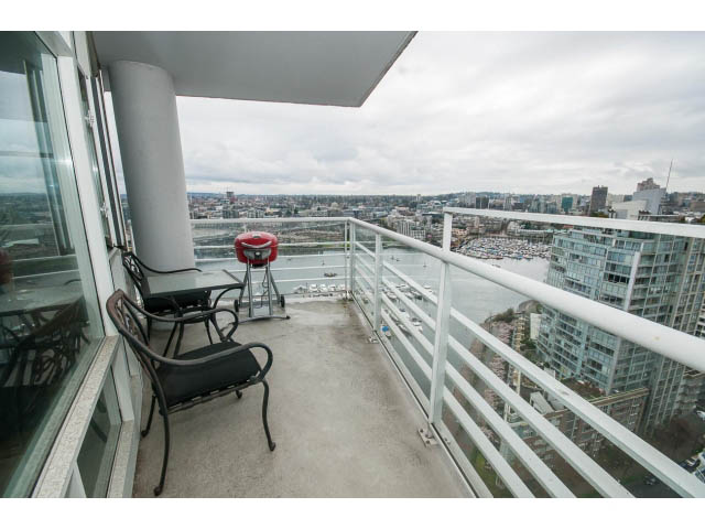 Furnished balcony with city view, modern furniture, and glass railings. - 2901 - 1199 Marinaside, Vancouver Downtown