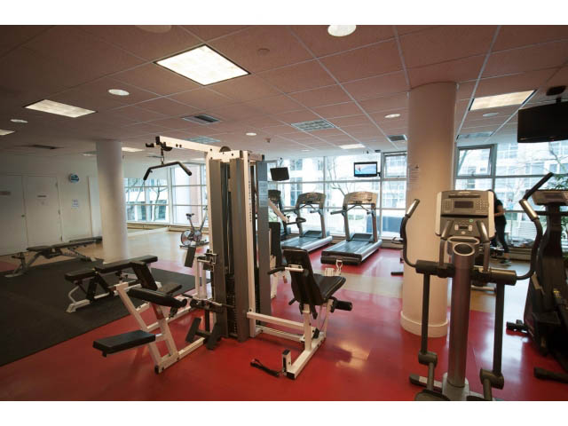 Furnished gym with cardio machines and weight equipment, red flooring, city view. - 2901 - 1199 Marinaside, Vancouver Downtown
