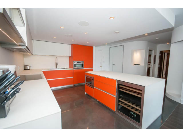 Bright kitchen with orange and white cabinets, stainless steel appliances, and a wine storage unit. - 806 - 518 Moberly Rd, Vancouver West Side