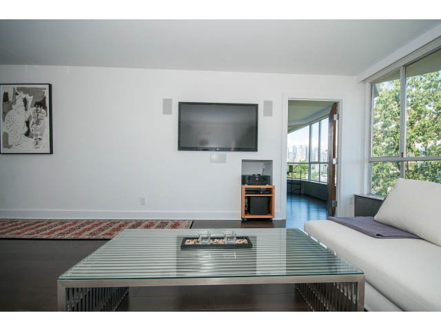 Bright living room with modern furniture, glass coffee table, and large windows offering a city view. - 806 - 518 Moberly Rd, Vancouver West Side