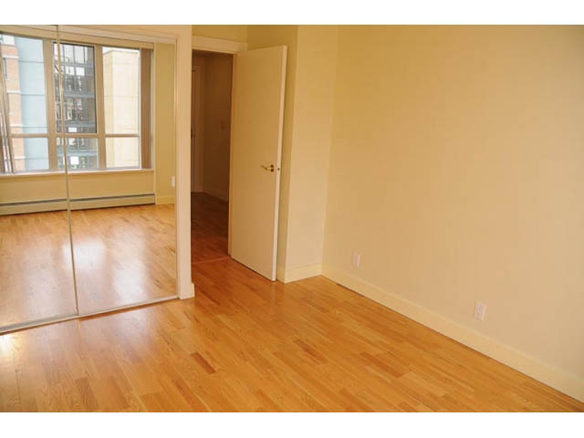 Bright living room with hardwood floors and sliding glass door leading to balcony. - 606-1228 Marinaside Crescent, Vancouver Downtown
