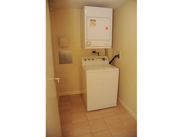 Laundry room with stacked washer and dryer, tiled floor, and utility cabinet. - 606-1228 Marinaside Crescent, Vancouver Downtown