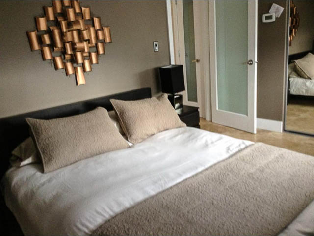 Furnished 1-bedroom bedroom with modern decor, neutral tones, and a large abstract wall art piece. - 501 - 1251 Cardero Street, Vancouver Downtown