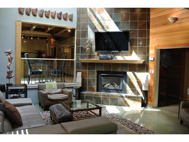 Spacious living room with modern decor, fireplace, and large TV. - 2450 Riverside Drive, North Vancouver