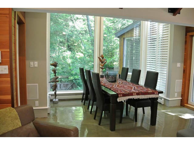 Spacious dining area with large windows, hardwood floors, and a view of greenery. - 2450 Riverside Drive, North Vancouver
