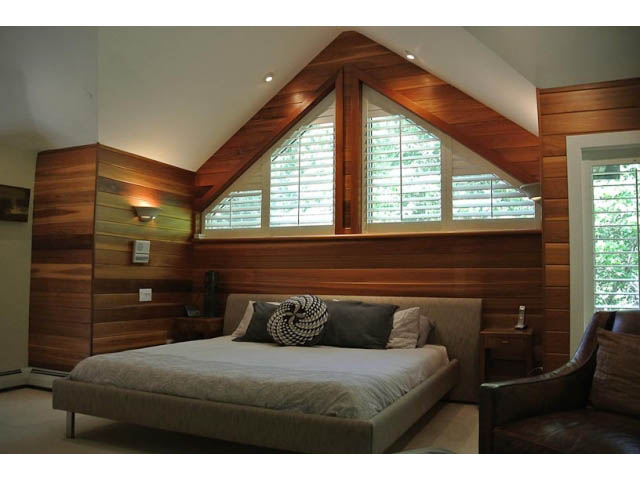 Spacious bedroom with wooden walls and large windows, modern furnishings. - 2450 Riverside Drive, North Vancouver