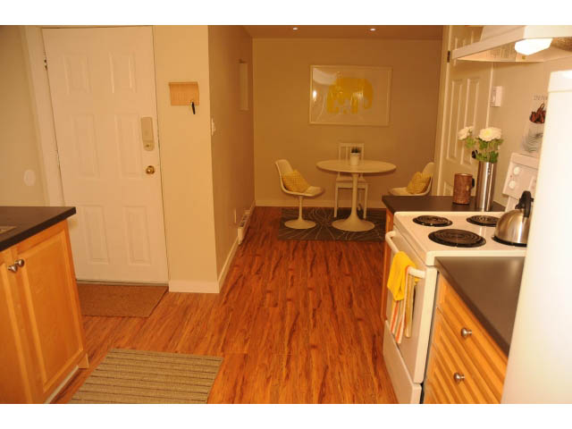Bright kitchen with wooden floors, modern appliances, and a cozy dining area. - Suite-942 Belvedere Drive, North Vancouver